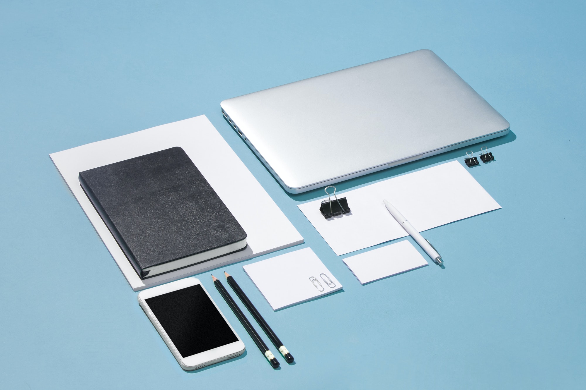 The laptop, pens, phone, note with blank screen on table